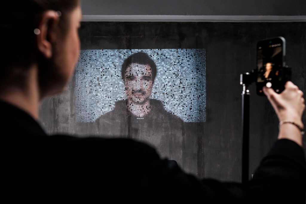 A visitor adds her photograph to the archive; the portrait rebuilds in real time